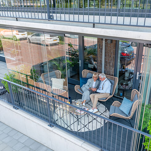Tevreden klanten genieten op hun balkon van hun balkonbeglazing
